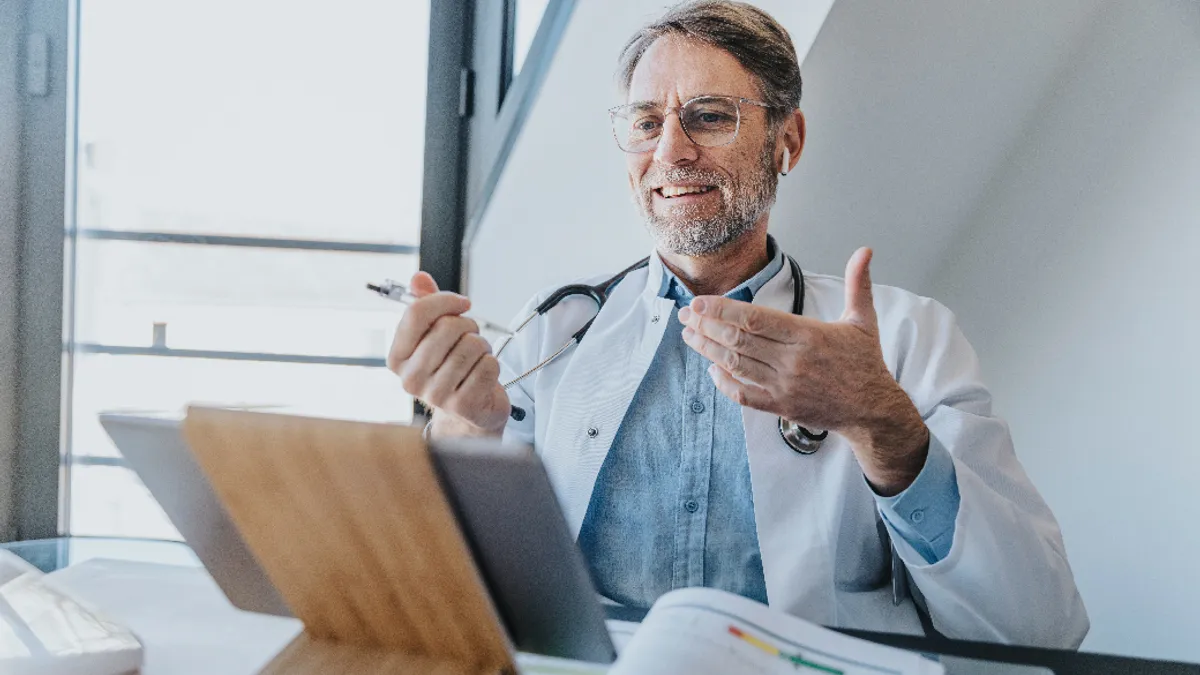 Smiling doctor discussing on video call over digital tablet while sitting at clinic