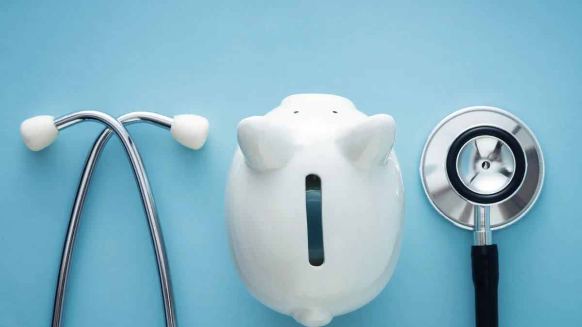 A birds-eye picture of a stethoscope and piggy bank against a blue background