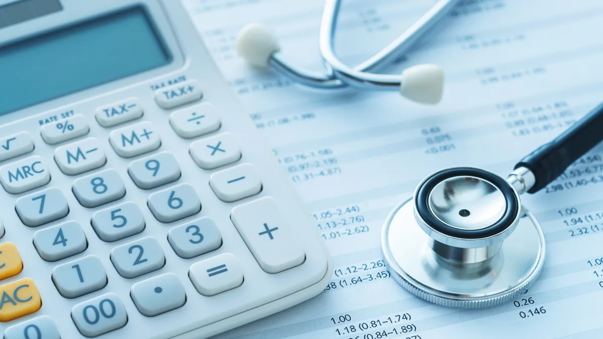 A calculator and stethoscope rest on a medical bill.