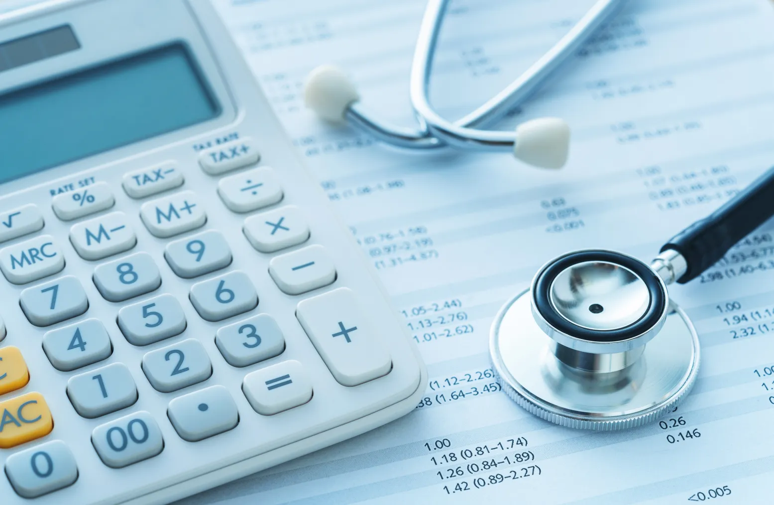 A calculator and stethoscope rest on a medical bill.