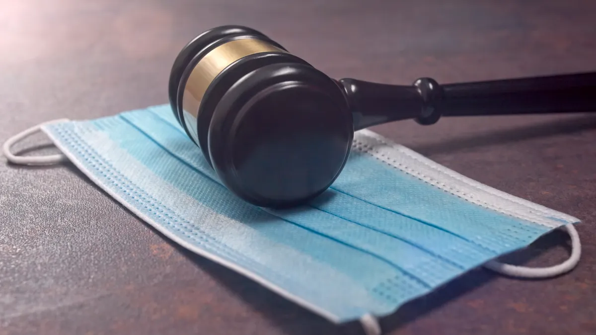 a gavel resting on a blue hospital face mask