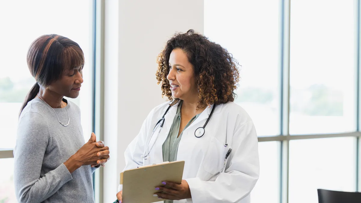 A female doctor and senior patient discuss medical records.