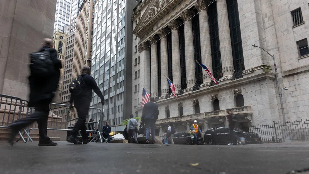 Several people walk by the New York Stock Exchange building