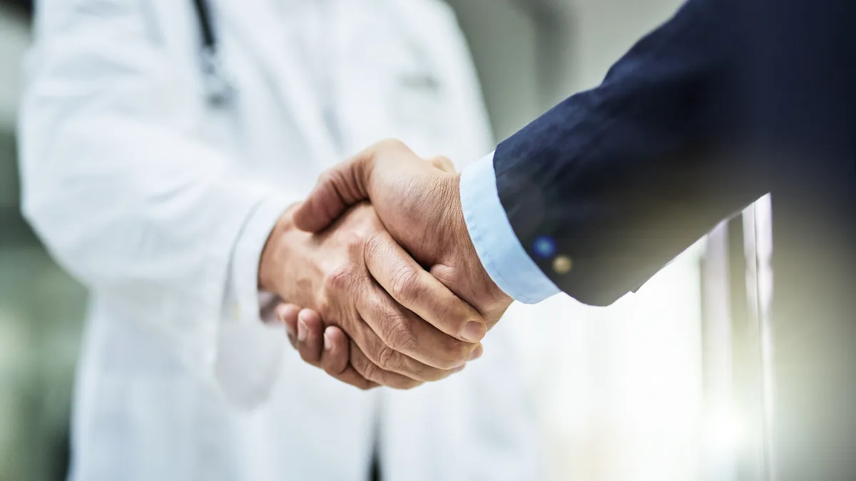 A doctor and a businessperson shaking hands.