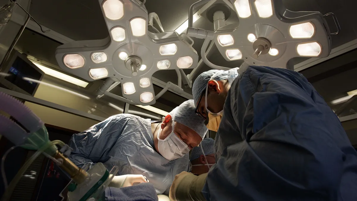 Two doctors hover over a patient in an operating room.