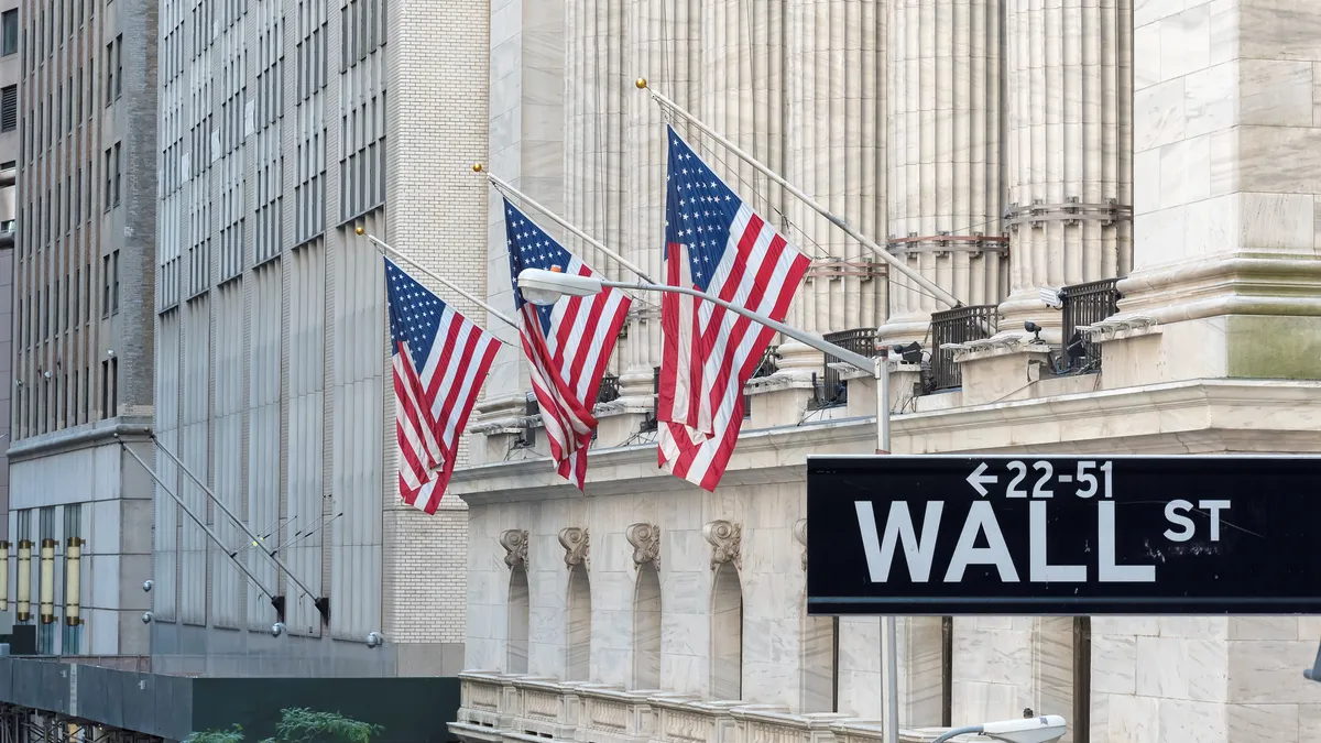 Wall Street sign with U.S. flags in background