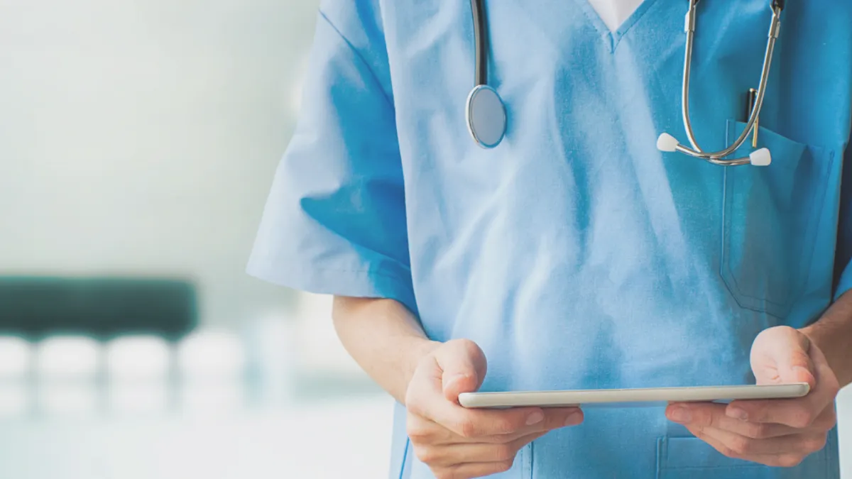 Healthcare professional holding a tablet.