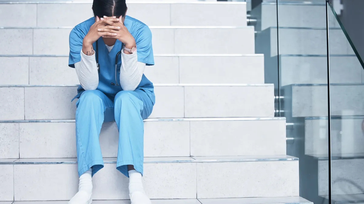 Shot of a female nurse looking stressed while sitting on a staircase stock photo