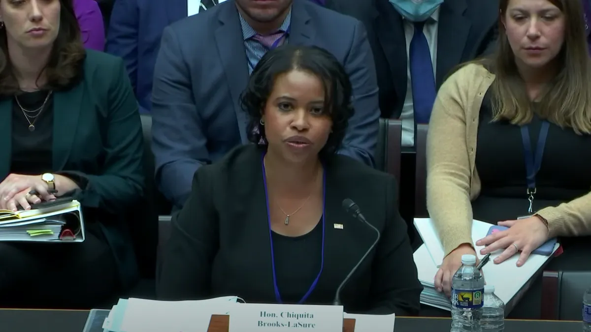 Chiquita Brooks-LaSure sits behind a desk testifying before a congressional subcommittee.